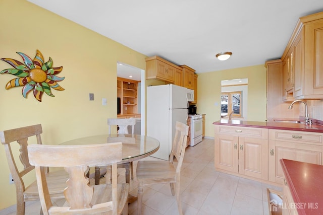 kitchen with white appliances, a sink, light tile patterned flooring, and light brown cabinetry