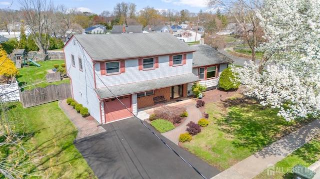 view of front of property with asphalt driveway, roof with shingles, a garage, and covered porch