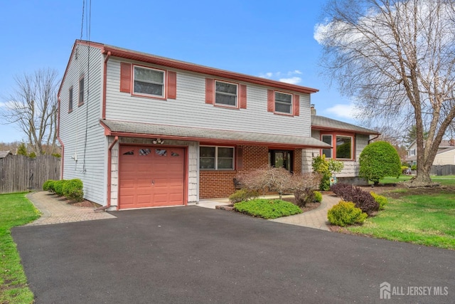 split level home featuring fence, driveway, and an attached garage