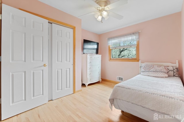 bedroom featuring wood finished floors, baseboards, ceiling fan, and a closet
