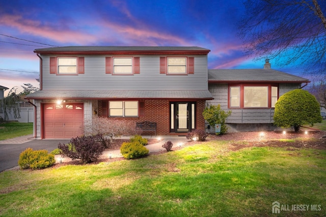 split level home featuring a garage, a lawn, and driveway