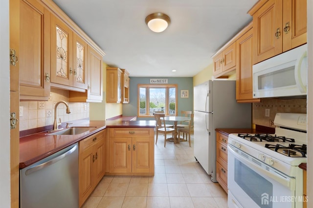 kitchen with white appliances, a sink, a peninsula, and dark countertops