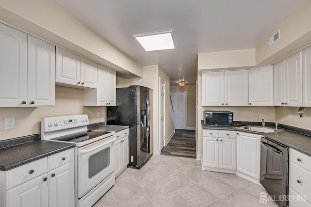 kitchen with white cabinetry, sink, black appliances, and light tile patterned flooring