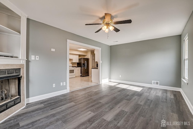 unfurnished living room featuring ceiling fan, hardwood / wood-style floors, and a fireplace