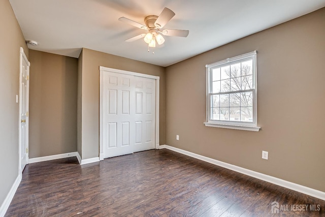 unfurnished bedroom with dark wood-type flooring, ceiling fan, and a closet