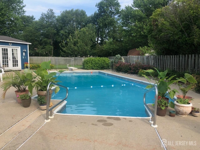 view of swimming pool with french doors, a diving board, and a patio area