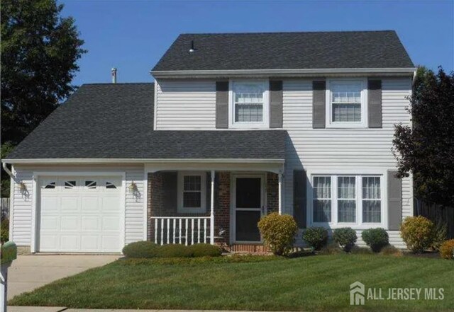 view of front of house featuring a garage, a front yard, and covered porch