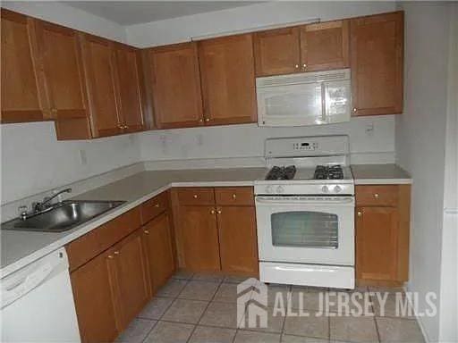 446 Great Beds Ct, Perth Amboy, NJ 08861 - kitchen with white appliances, light countertops, and brown cabinets