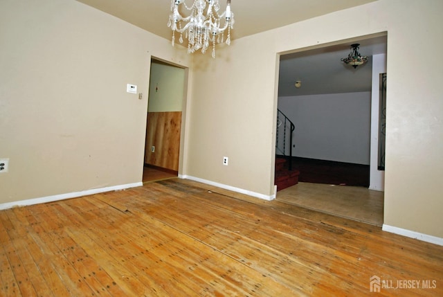 empty room featuring hardwood / wood-style floors and a notable chandelier