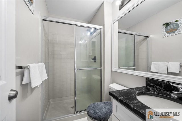 bathroom featuring vanity, a shower stall, and toilet