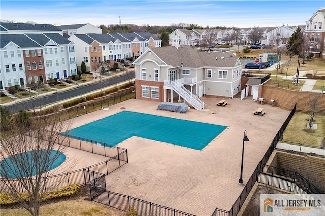 view of swimming pool with a residential view, fence, and stairway