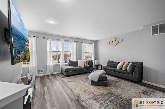 living area featuring wood finished floors, visible vents, and baseboards