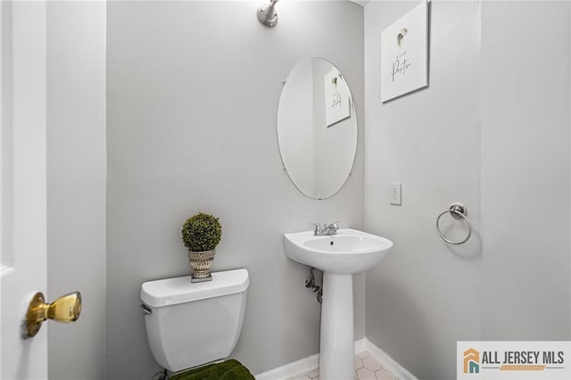 bathroom featuring toilet, baseboards, and a sink