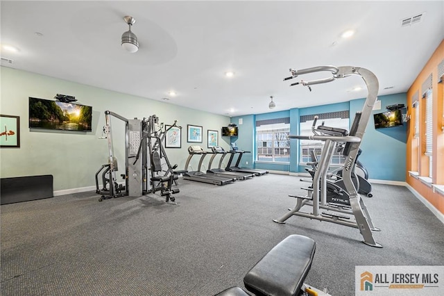 exercise room with baseboards, visible vents, and ceiling fan