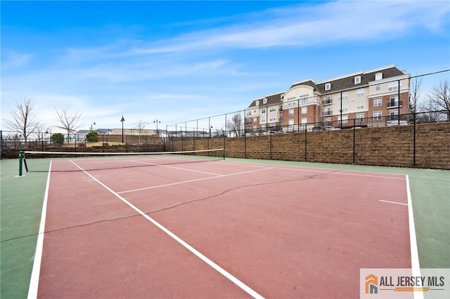 view of tennis court featuring community basketball court and fence