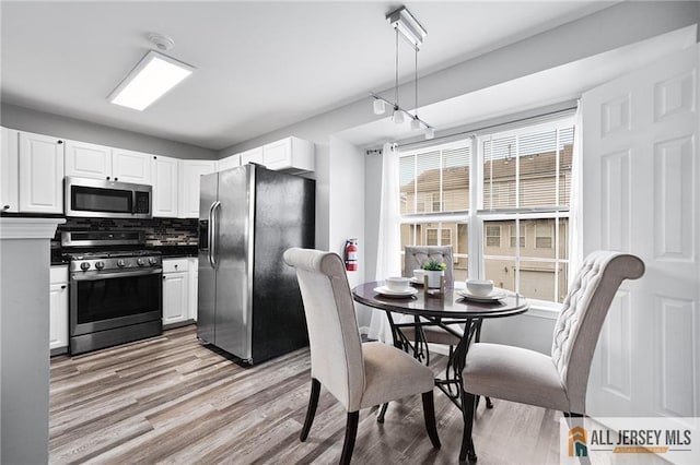 kitchen featuring appliances with stainless steel finishes, light wood-type flooring, backsplash, and white cabinetry