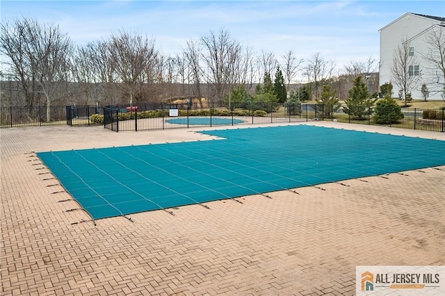 community pool with a patio area and fence