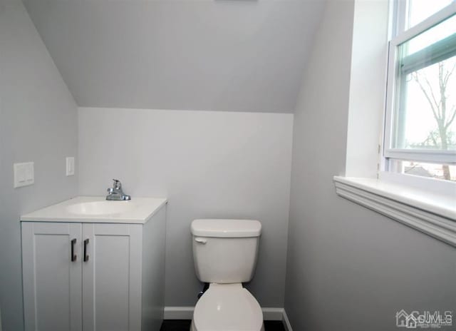 bathroom featuring vaulted ceiling, toilet, and vanity