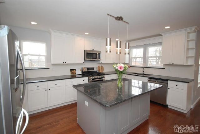 kitchen featuring dark hardwood / wood-style floors, stainless steel appliances, hanging light fixtures, and white cabinets