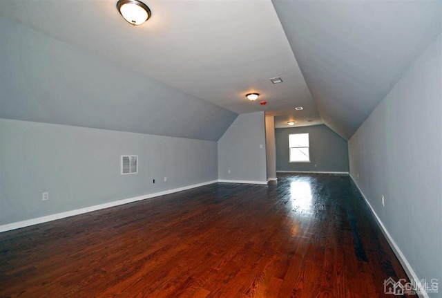 additional living space with hardwood / wood-style flooring and vaulted ceiling