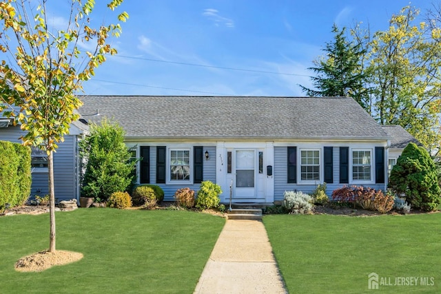 view of front of property featuring entry steps, a front lawn, and a shingled roof