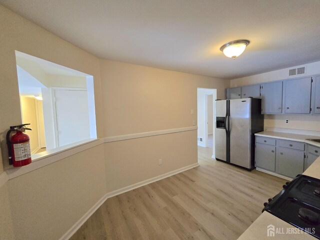 kitchen with gray cabinetry, stainless steel fridge, and light wood-type flooring