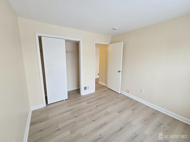 unfurnished bedroom featuring light hardwood / wood-style floors and a closet