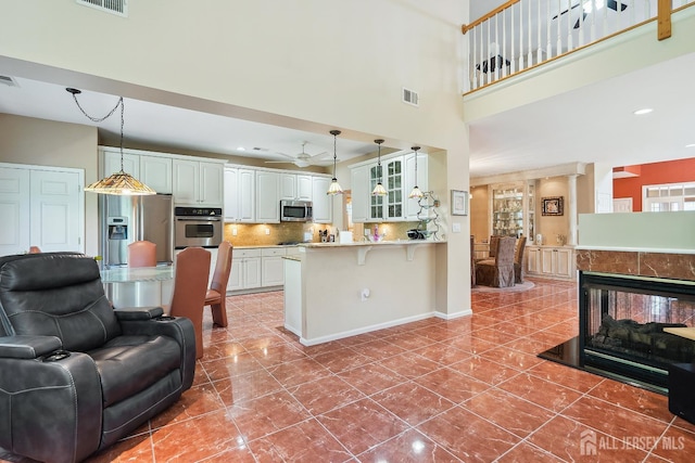 267 Tyler Ct, Monroe, NJ 08831 - kitchen featuring stainless steel appliances, a peninsula, glass insert cabinets, a kitchen breakfast bar, and a high ceiling