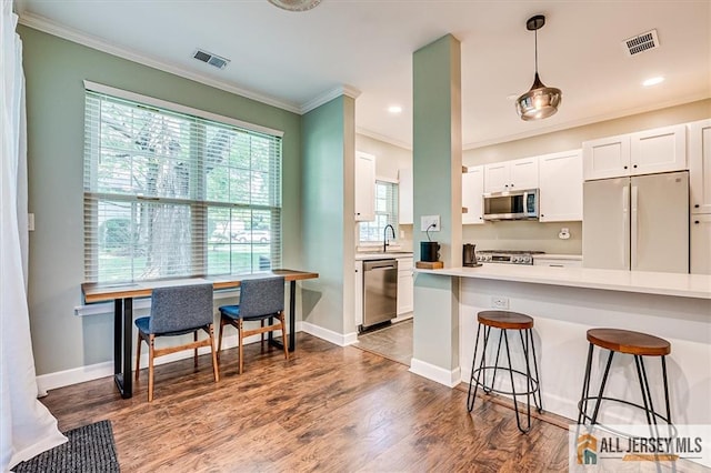 4211 Bayberry Ct, South Brunswick, NJ 08852 - kitchen with appliances with stainless steel finishes, ornamental molding, a kitchen bar, white cabinets, and light countertops