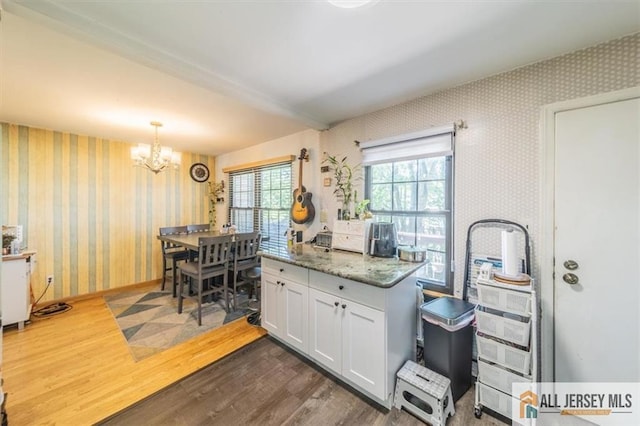 47 Pheasant Run Unit 47, Edison, NJ 08820 - kitchen featuring wallpapered walls, dark wood-style floors, a chandelier, white cabinets, and pendant lighting
