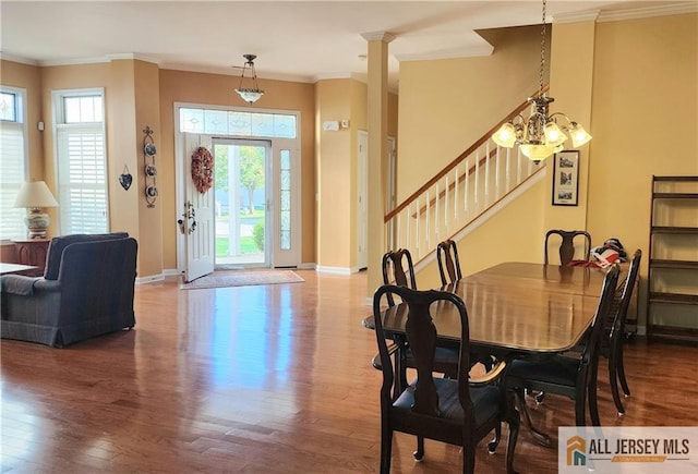 dining space with wood-type flooring, ornamental molding, and a chandelier