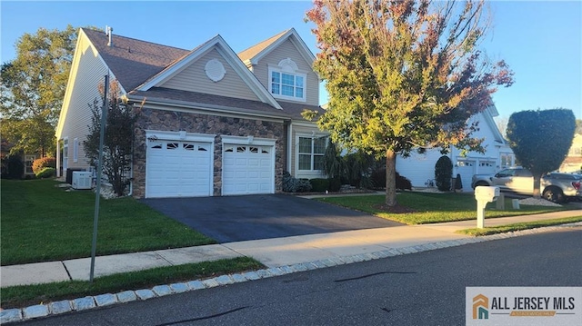 view of front of property with stone siding, a front lawn, driveway, and central air condition unit