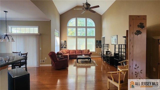 living area with visible vents, wood finished floors, high vaulted ceiling, baseboards, and ceiling fan with notable chandelier