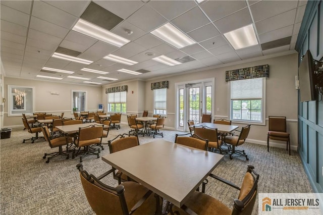 carpeted dining space featuring a drop ceiling