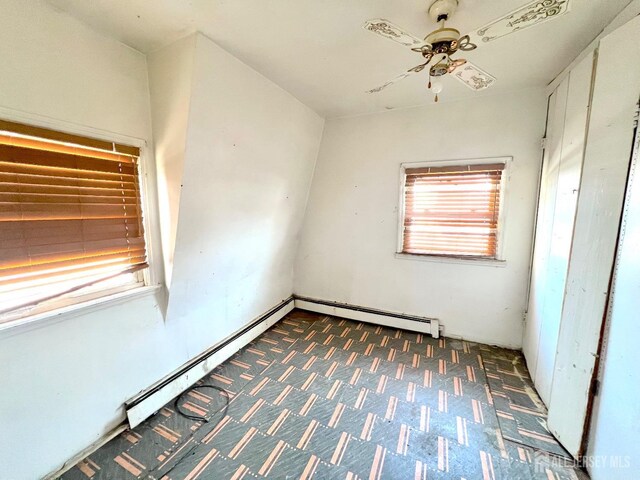 unfurnished bedroom featuring a baseboard heating unit and ceiling fan