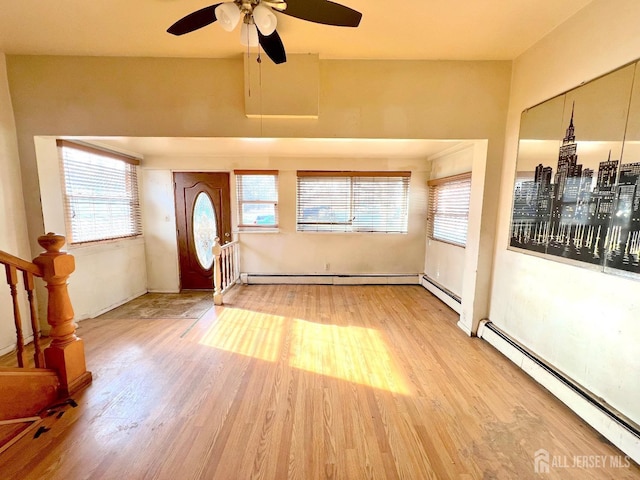 foyer entrance with a baseboard heating unit, a healthy amount of sunlight, and wood finished floors