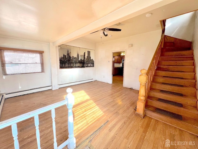 spare room with baseboard heating, light wood-style flooring, stairs, and ceiling fan