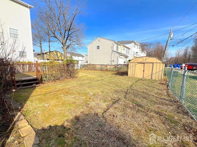 view of yard featuring a deck, a gate, fence, a storage shed, and an outdoor structure