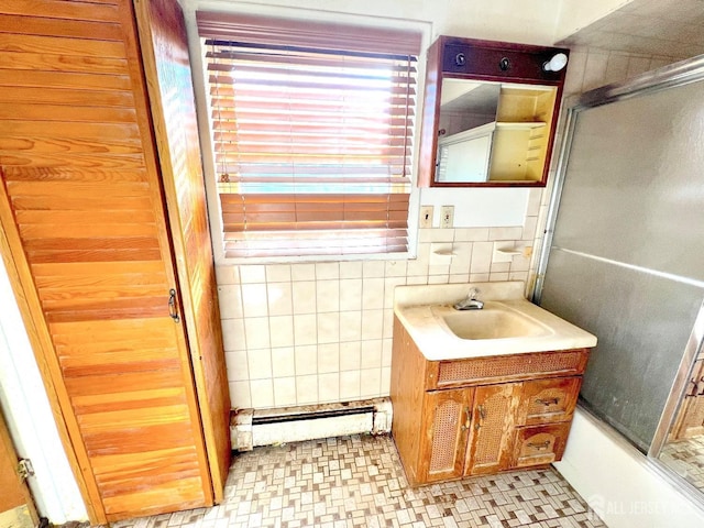 full bathroom with combined bath / shower with glass door, a baseboard heating unit, tile walls, and vanity