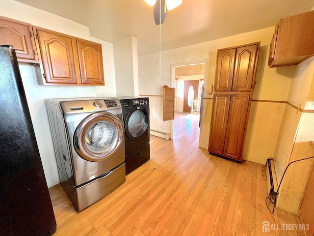 washroom featuring ceiling fan, washer and clothes dryer, baseboard heating, light wood-style floors, and cabinet space