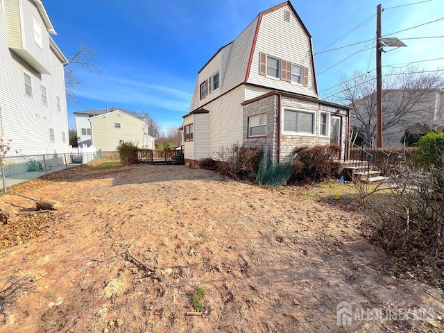 back of property with a gambrel roof and fence