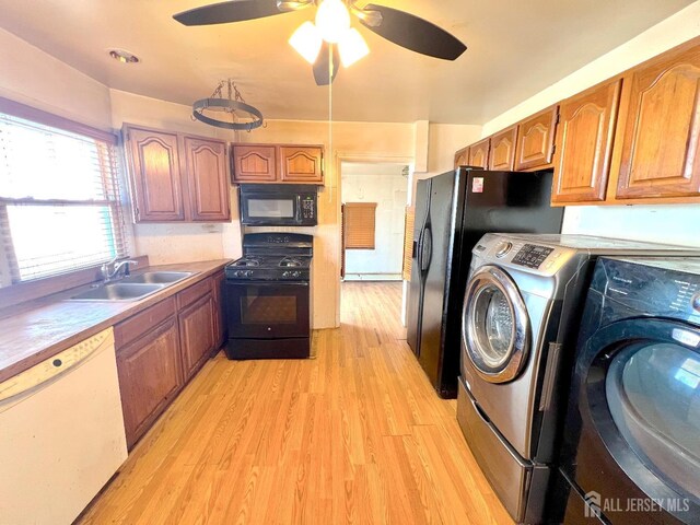 laundry area featuring ceiling fan, light wood-type flooring, laundry area, washer / clothes dryer, and a sink