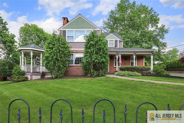 241 E Chestnut Ave, Metuchen, NJ 08840 - victorian home with covered porch, brick siding, a front yard, and a chimney