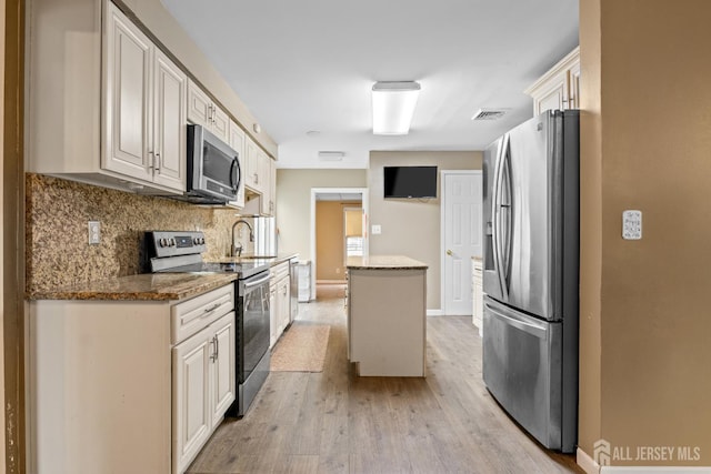 15 Cutter Ave, Fords, NJ 08863 - kitchen featuring appliances with stainless steel finishes, a center island, light wood-style flooring, backsplash, and stone counters