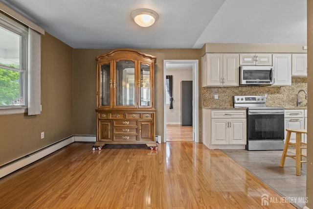 15 Cutter Ave, Fords, NJ 08863 - kitchen with stainless steel appliances, white cabinets, a baseboard radiator, backsplash, and light wood-style flooring
