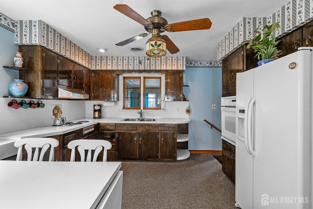 kitchen featuring white appliances, a sink, light countertops, dark brown cabinets, and under cabinet range hood