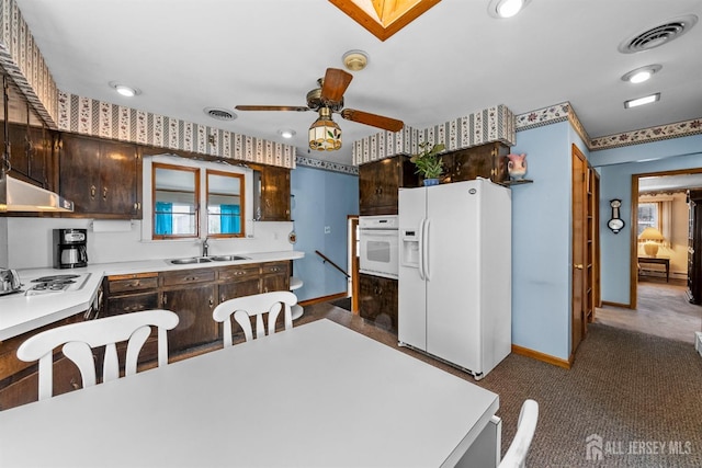 kitchen featuring white appliances, visible vents, a sink, dark brown cabinetry, and under cabinet range hood