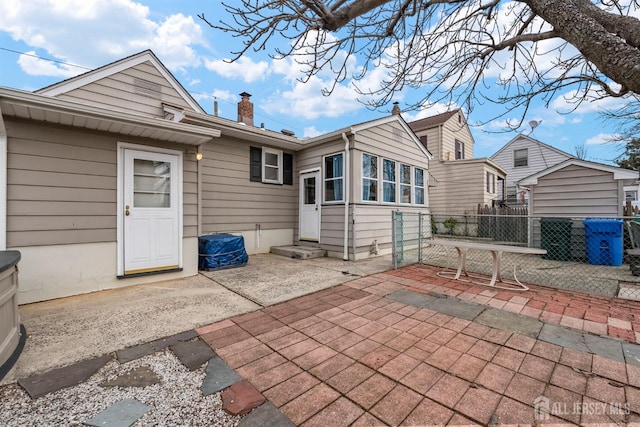 rear view of property with entry steps, a patio area, fence, and a chimney