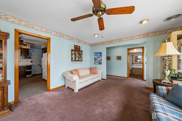 carpeted living area with visible vents, baseboards, and ceiling fan