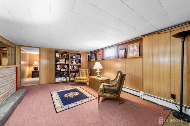 sitting room featuring built in features, a baseboard radiator, carpet floors, and wood walls